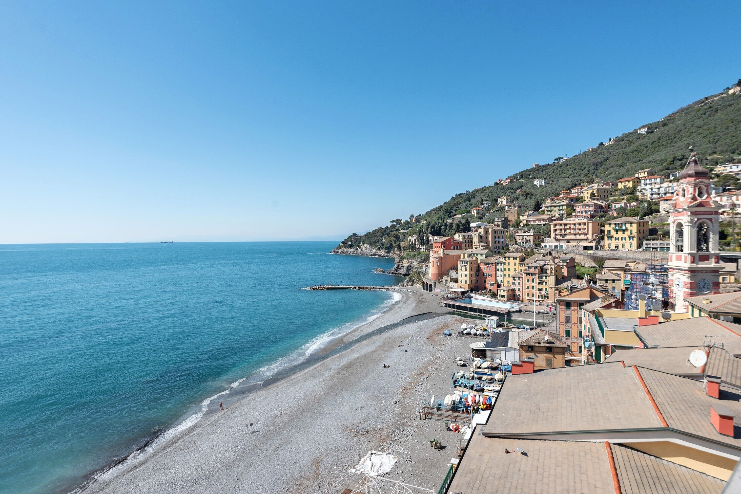 A coastal town with buildings along the beach, a clear sky, and a calm sea.