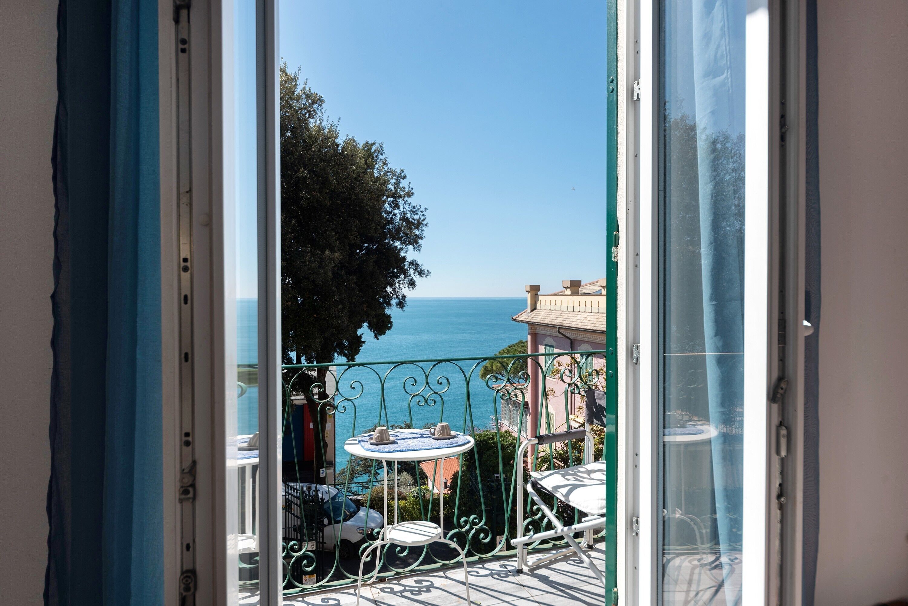 Un balcone con vista sul mare, un tavolo con sedie e un parapetto.