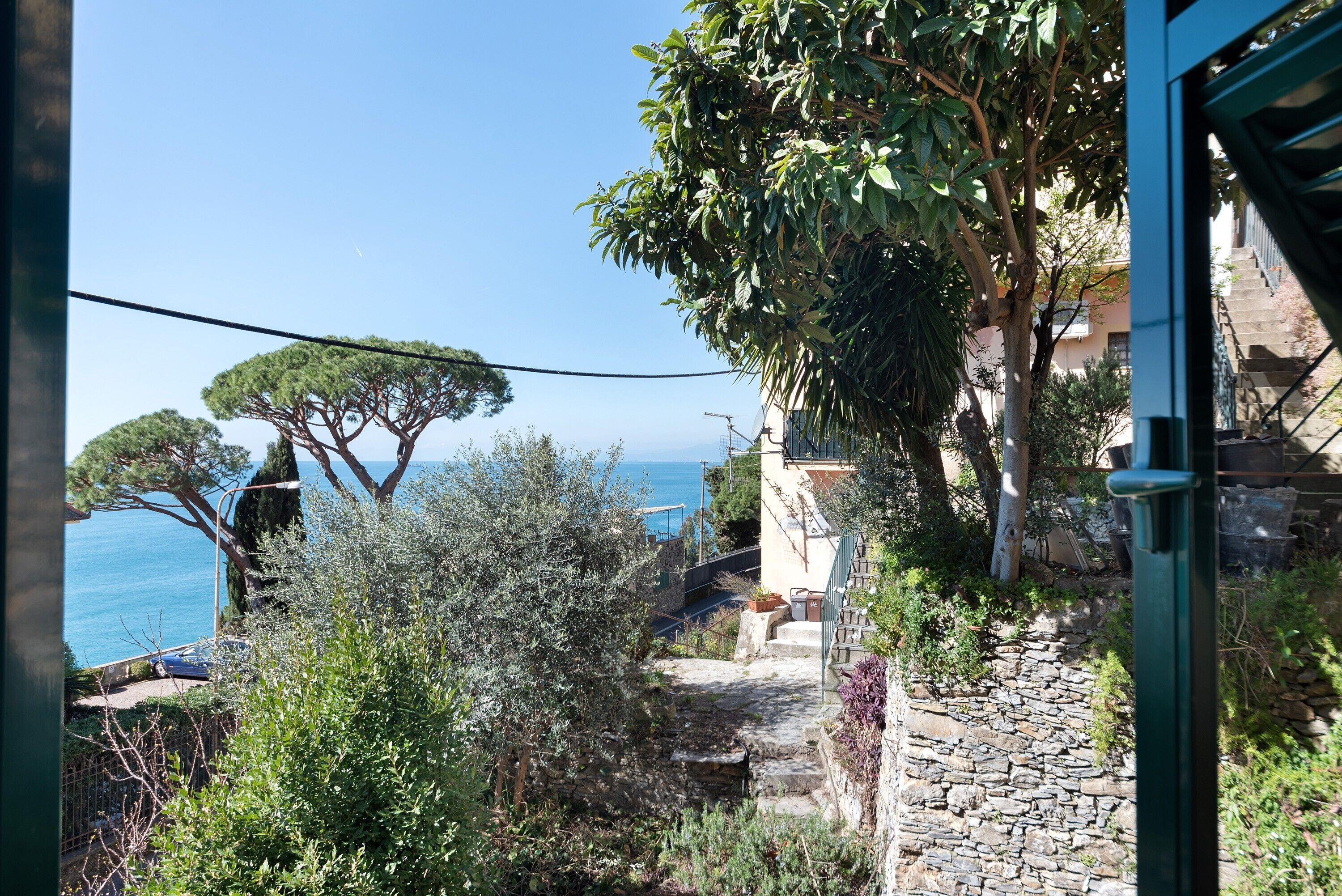 Un viale in pietra conduce a un edificio con vista sul mare.