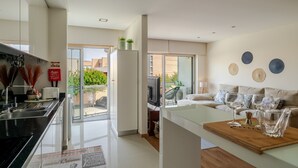 Una cocina moderna con comedor, refrigerador, televisor y sofá con adornos decorativos.