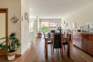 A modern kitchen with wooden cabinets, a dining area with a table and chairs, and a large window with a view of greenery. - Apartment 'Estrelinha Do Mar' with Shared Pool, Wi-Fi and Air Conditioning (Apúlia)