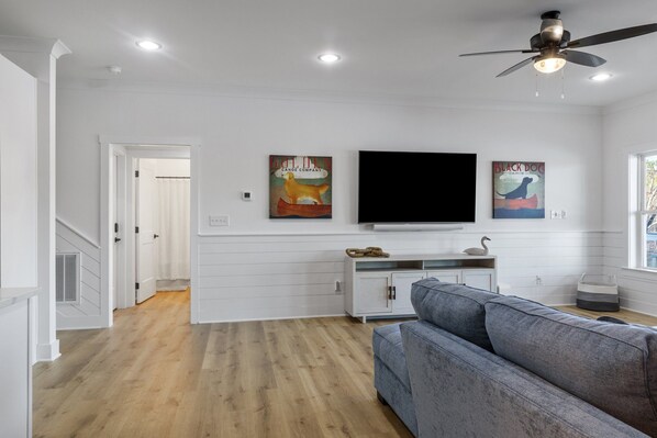 A modern living room with a grey sofa, a flat-screen TV, and artwork on the wall.