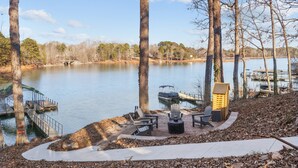 Une terrasse au bord du lac avec des sièges extérieurs, un quai et un petit bâtiment.