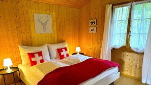 A wooden-paneled bedroom with a bed, pillows, a blanket, a lamp, and a rug. - Concierge, Scenic Views, Long Stay by SwissHut (Sigriswil)