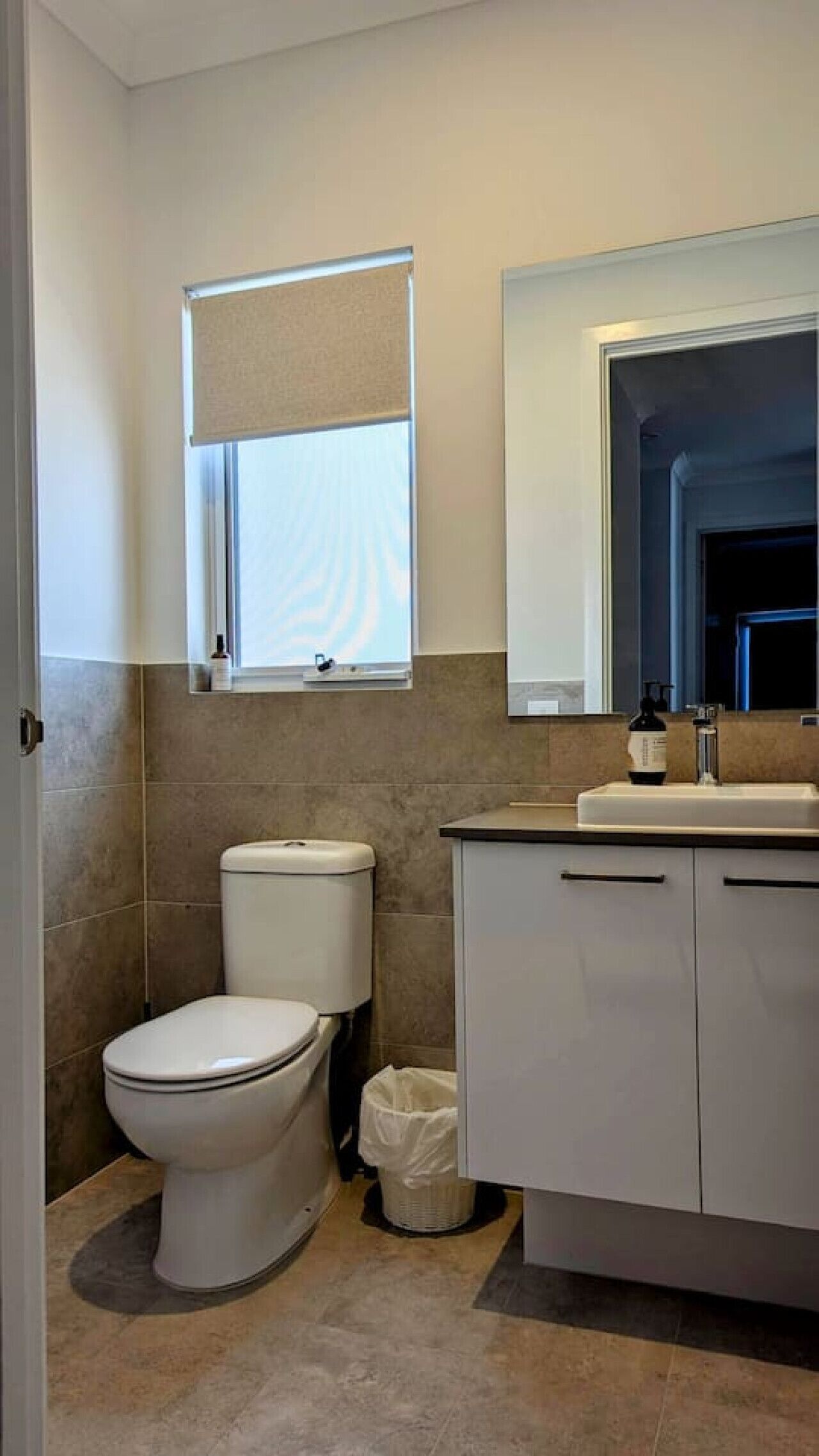 Une salle de bain moderne équipée de toilettes, d’un lavabo et d’un miroir.