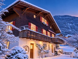 Eine Chalet mit einem Holzbalkon, verschneiter Umgebung und Bergblick.
