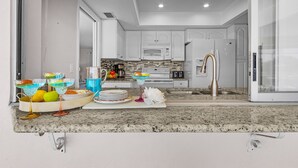 Una cocina moderna con armarios blancos, un microondas y un refrigerador de acero inoxidable.