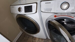 Lavadora y secadora Samsung de carga frontal en un cuarto de lavado con piso de baldosas.