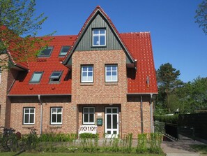 Un bâtiment à deux étages, doté d’un toit recouvert de tuiles rouges, de nombreuses fenêtres et d’une façade en briques.