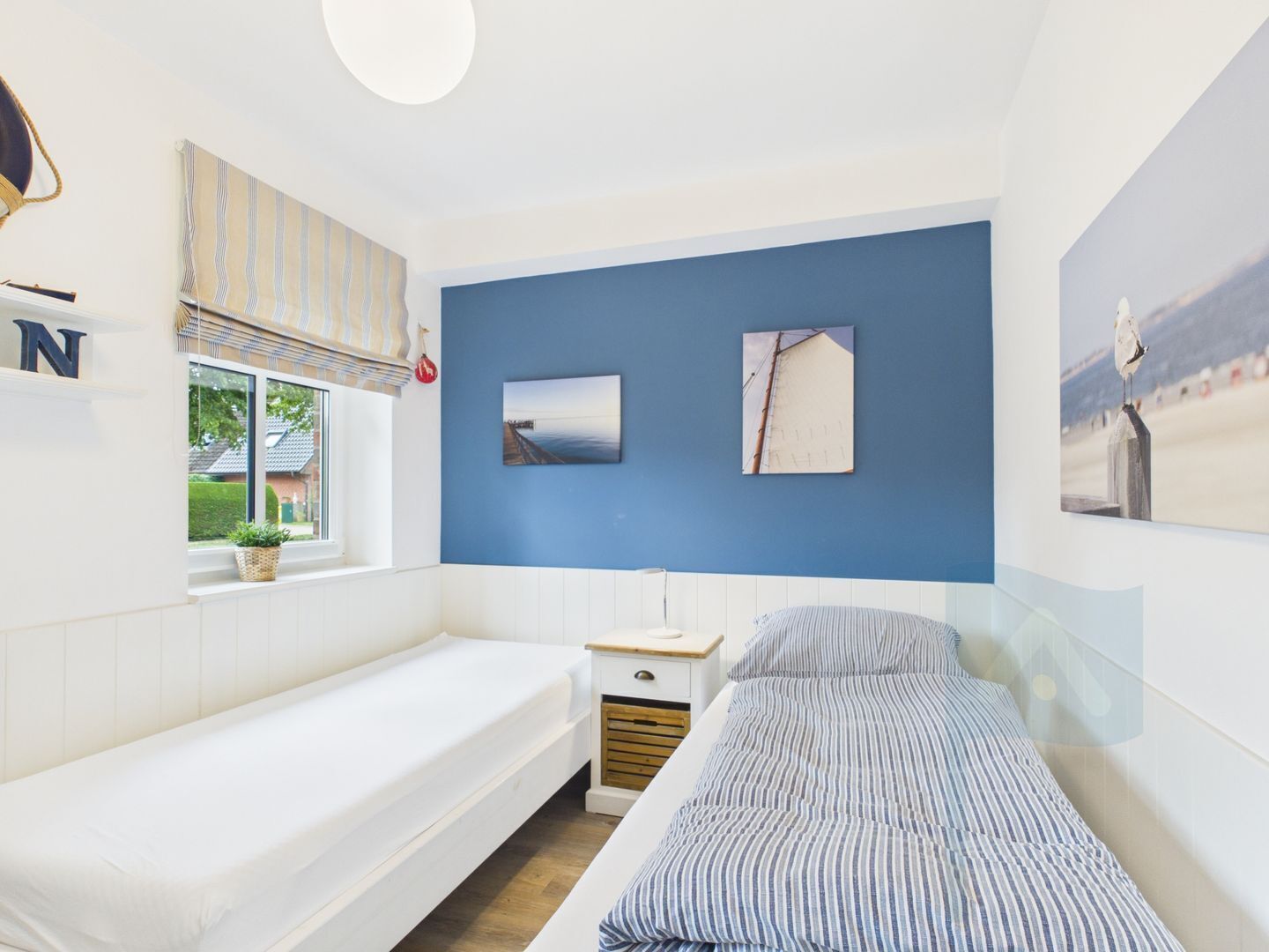 Un dormitorio con cama, mesita de noche, ventana con vistas y decoración en la pared.