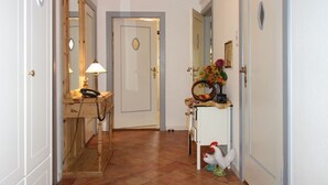 Un pasillo con un escritorio de madera, un teléfono, un espejo y una estatua decorativa de gallo.