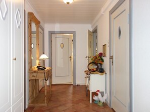 A hallway with a wooden desk, a telephone, a mirror, and a decorative rooster statue.