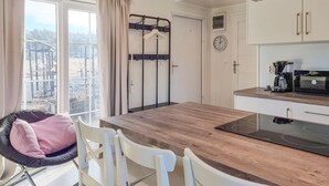A modern kitchen with a wooden table, white chairs, a hanging clothes rack, and a view of a cityscape through large windows. - 1 bedroom awesome home in Klövedal (Klövedal)