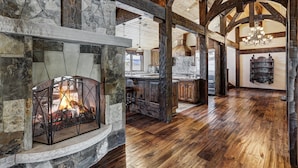 A spacious kitchen with a stone fireplace, wooden beams, and a large chandelier. - Long Ridge Lodge | Heavenly Views and Private Spa, Quiet Neighborhood. (Breckenridge)