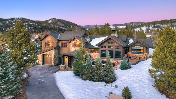 A large, multi-story house with a stone facade, a driveway, and snow-covered surroundings. - Long Ridge Lodge | Heavenly Views and Private Spa, Quiet Neighborhood. (Breckenridge)