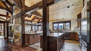A spacious kitchen with a large island, wooden beams, stone accents, and a view of the mountains. - Long Ridge Lodge | Heavenly Views and Private Spa, Quiet Neighborhood. (Breckenridge)