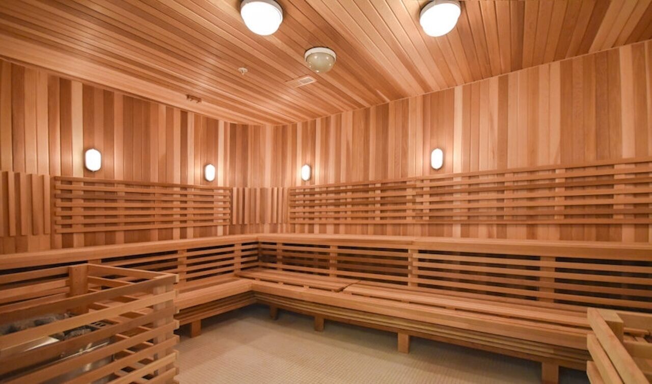 Una sauna con bancos de madera y paredes de listones, con luces en el techo.