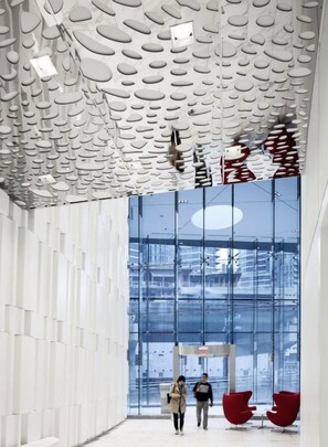 A modern interior with a unique ceiling design, large glass windows, and red chairs. - Beautiful Luxurious Modern Suite (Toronto)