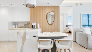 Eine moderne Küche mit weißen Schränken, einer Marmorarbeitsplatte und einer Wand in Holzoptik.
