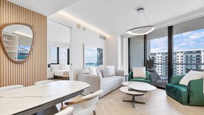 Ein modernes Wohnzimmer mit Essbereich, großen Fenstern und Blick auf Gebäude.