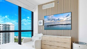 Ein modernes Schlafzimmer mit einem großen Fenster mit Blick auf Stadt und Meer.