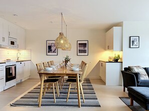 Una cocina moderna con armarios blancos, una mesa de comedor preparada para cuatro personas y una lámpara colgante.