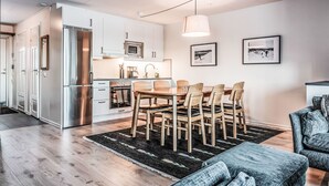 Une cuisine moderne dotée d’appareils électroménagers en acier inoxydable, un coin repas avec des chaises en bois et un tapis noir et blanc.