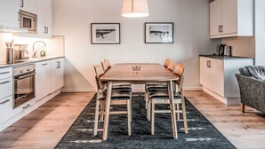 Une cuisine moderne avec un coin repas, comprenant une table en bois, des chaises et un tapis noir.