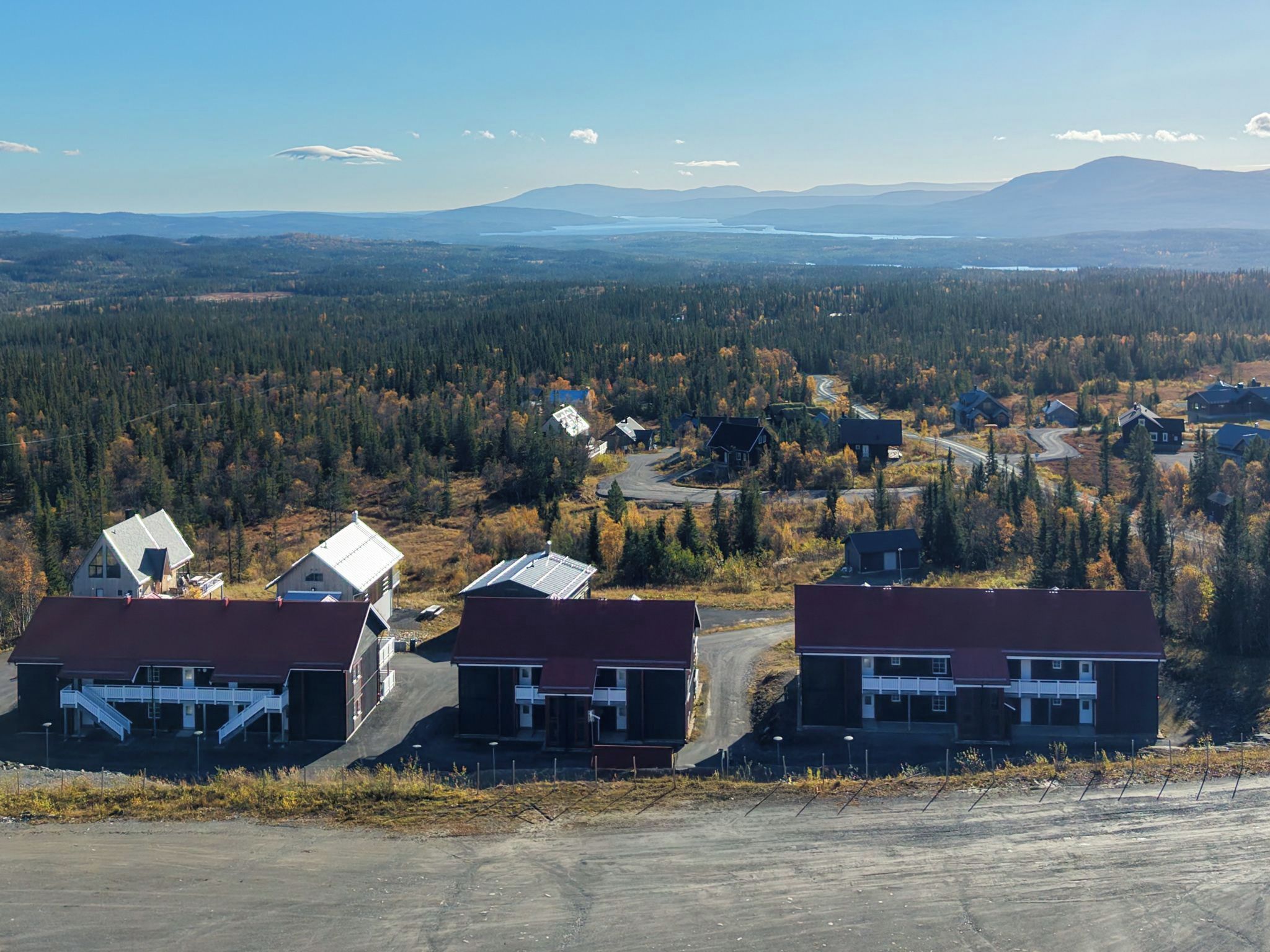 A residential area with houses, a road, and a forested landscape.