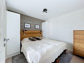 A bedroom with a bed, a wooden headboard, a dresser, and two framed pictures on the wall.