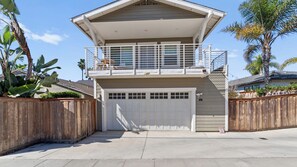 Une maison à deux étages avec un balcon, un garage et une clôture en bois.