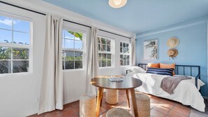 Une chambre avec un lit, une table et une vue sur l’extérieur grâce à de grandes fenêtres.