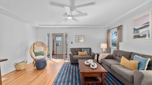 A living room with a sofa, armchair, coffee table, and a ceiling fan.