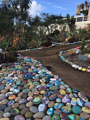 Un sendero de jardín con rocas pintadas de colores y diversas plantas.