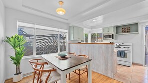 Een moderne keuken met witte kasten, een houten eettafel en een groot raam.