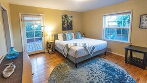 A bedroom with a bed, a nightstand, a lamp, a window, and a door. - Walk to the beach! The Moonlight Beach Bungalow (Encinitas)
