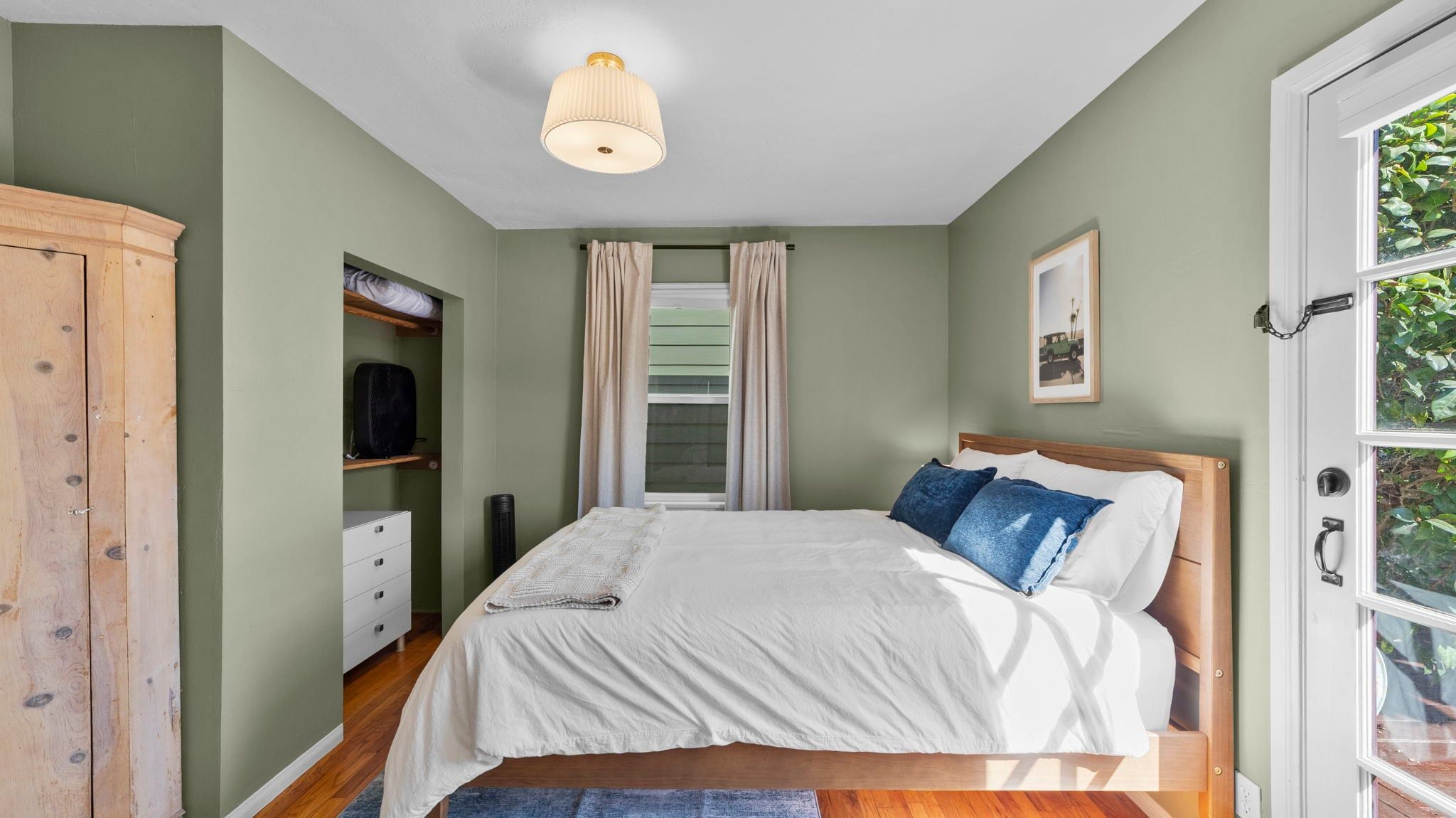 Quarto com cama, guarda-roupa, janela com cortinas e luminária no teto.