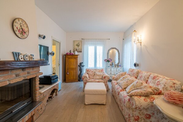 A living room with a fireplace, a sofa, a chair, and a mirror.