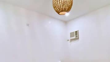 Habitación de hotel con dos camas de madera, ropa de cama blanca y una lámpara de techo tejida.