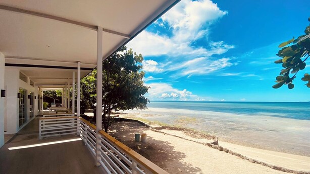 A covered walkway leading to a beach with a clear view of the ocean and a tree on the right. - Mandala Beach Cebu by Hiverooms (Daanbantayan)