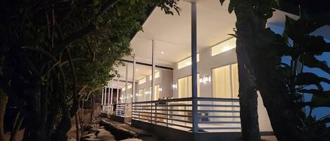 A modern hotel with a covered walkway, large windows, and indoor lighting.