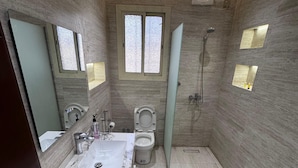 Un baño moderno con lavamanos de mármol, inodoro y ducha.