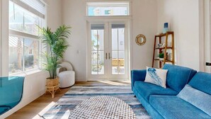 Un salon spacieux avec un canapé bleu, un fauteuil blanc et une grande plante en pot.