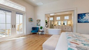Une pièce spacieuse avec un grand lit, un fauteuil bleu et une petite table sur laquelle est posée une plante.