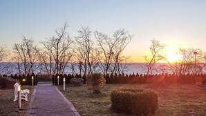 Un camino pavimentado que lleva a un banco y una vista del atardecer sobre el agua.