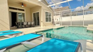 A pool area with lounge chairs and a ceiling fan. - Highlands Reserve Villa with screened-in patio & pool. Peaceful Golf Community. (Davenport)