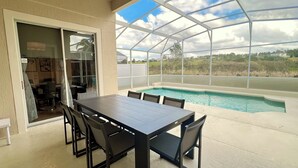 A covered patio with a pool, a dining table, and chairs. - Highlands Reserve Villa with screened-in patio & pool. Peaceful Golf Community. (Davenport)