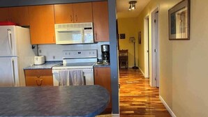 A kitchen with wooden cabinets, a white refrigerator, a microwave, and a stove.