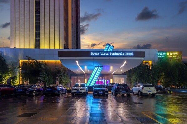 The exterior of Buena Vista Peninsula Hotel with a modern design, a parking lot, and a sign indicating a spa and pet-friendly policy. - Yantai Lijing Peninsula Hotel (Yantai)