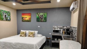 Une chambre d’hôtel avec un lit, une petite kitchenette et trois tableaux accrochés au mur.